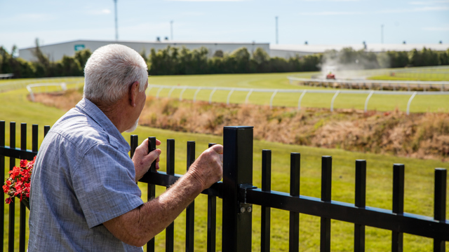 Man on a gate looking at a race course